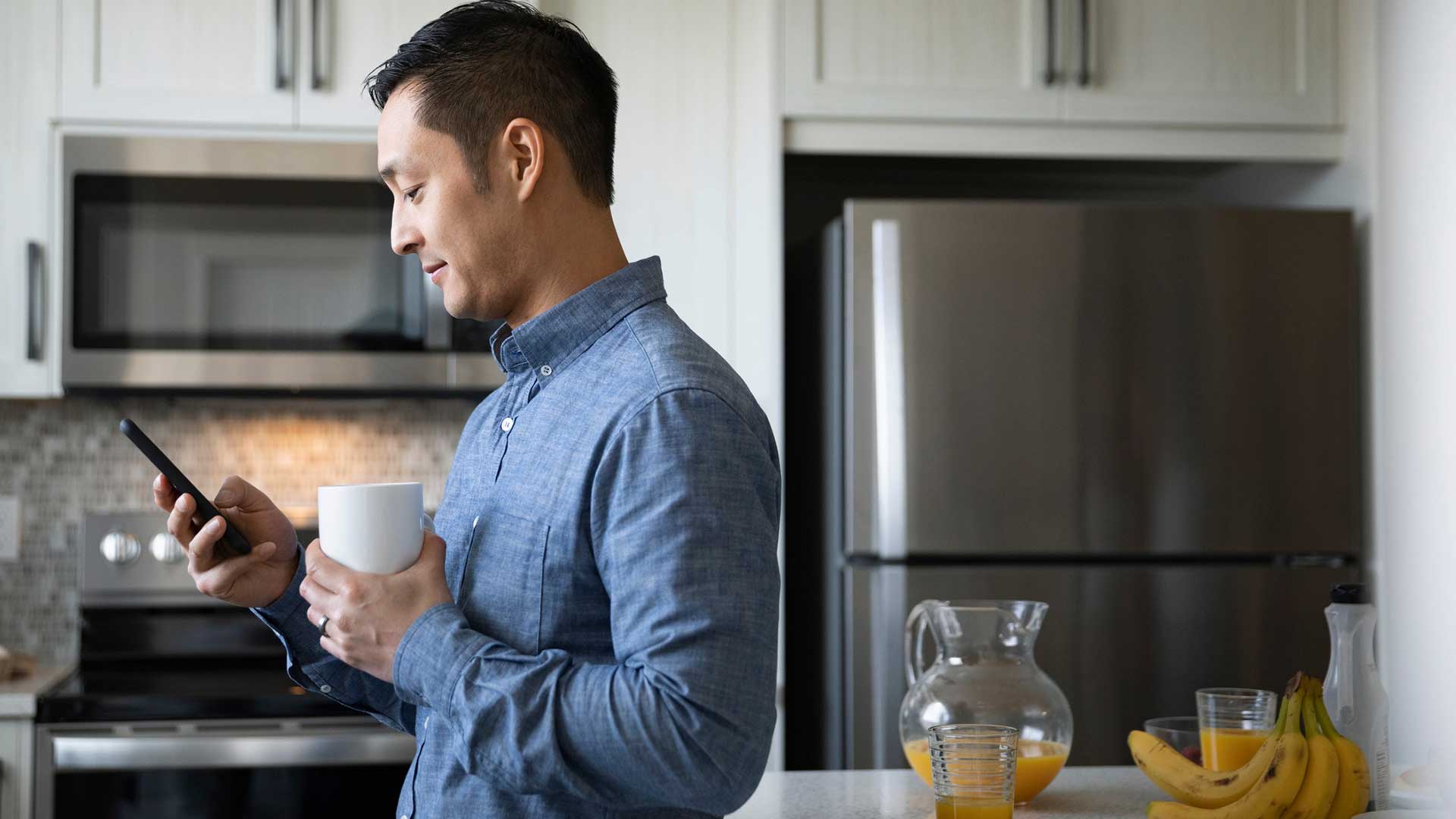 手握咖啡杯看手机的男士；图片用于先存钱，还是先还债？